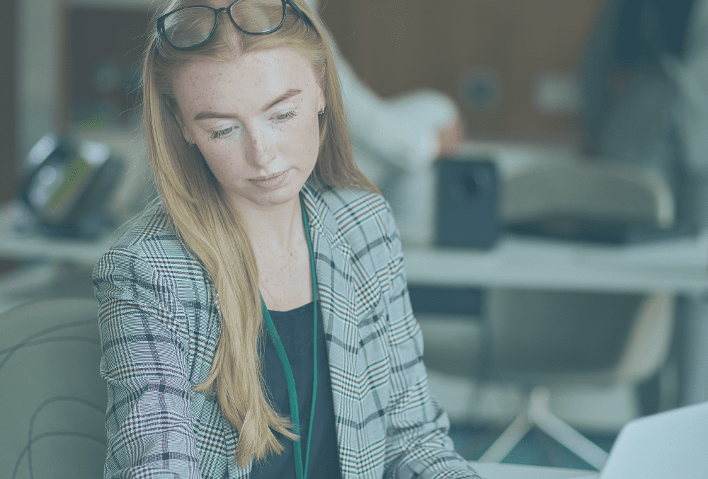 A young female business woman on a business administration apprenticeship sitting at a desk and looking at paperwork