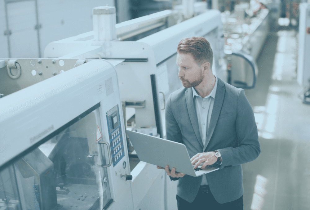 An improvement technician checks modern machinery whilst checking against a laptop