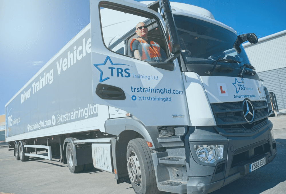 A LGV with the door open and a TRS driver trainer standing up at the cab