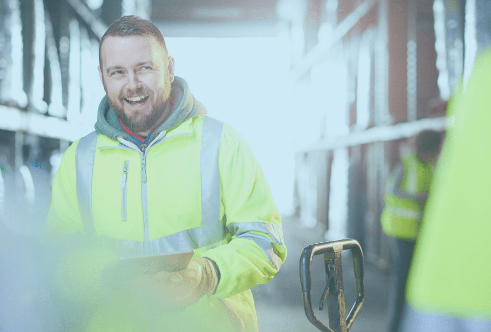 A supply chain warehouse operative smiling in a warehouse