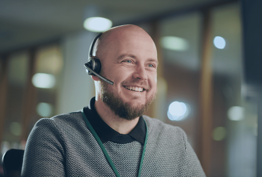 middle aged man smiling with headset on in an office environment