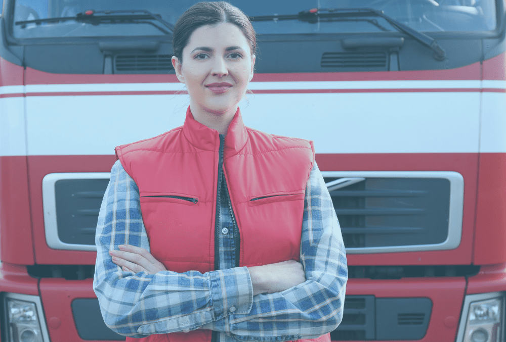 Smiling female HGV driver standing in front of a truck