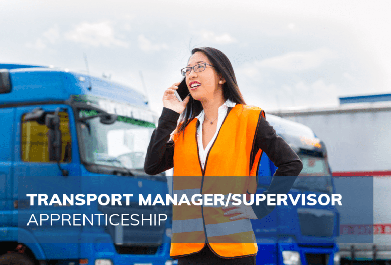 woman in hi vis jacket outside with lorries on mobile phone smiling