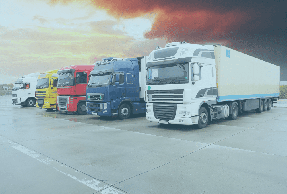three large HGV trucks lined up outside against a red sky